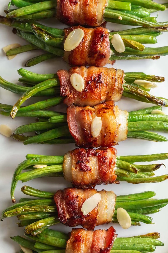 white plate filled with bacon wrapped green beans christmas food ideas garnished with silvered almonds