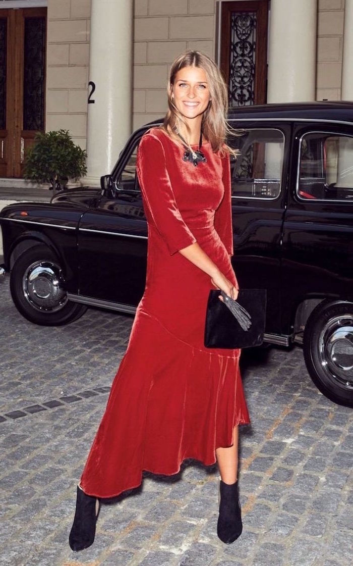 woman with shoulder length blonde hair long sleeve wedding guest dresses wearing red velvet dress with black velvet boots and bag