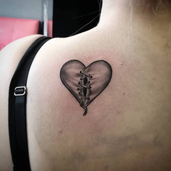 back tattoo of heart with black outlines gray shadows heart tattoo on hand held together with bandages