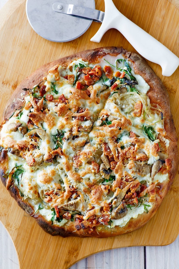 bacon and chicken pizza with cheese homemade pizza recipe with basil placed on wooden cutting board