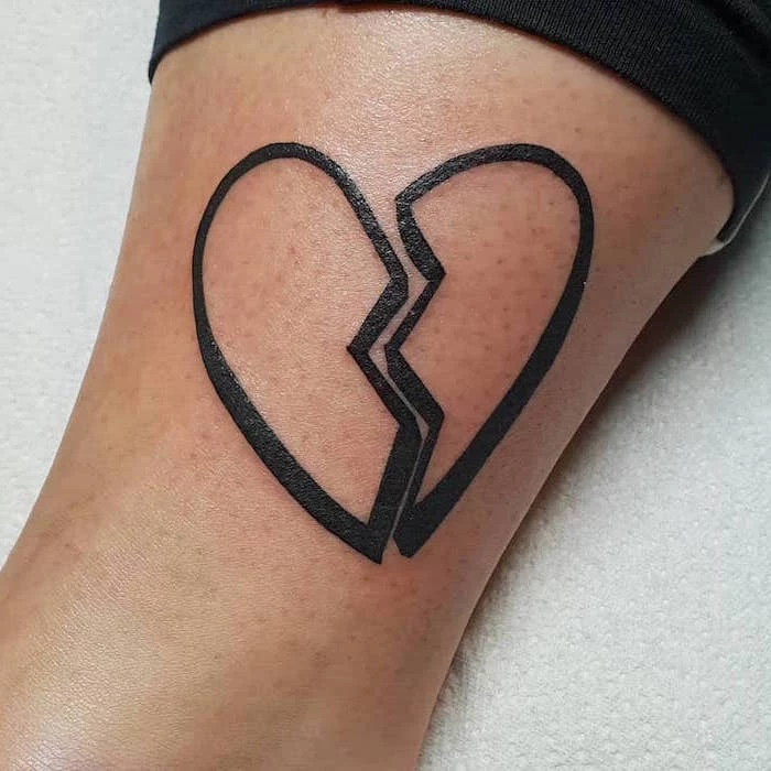 black putline of two pieces of a heart separated in the middle heart tattoos with names inside the leg tattoo