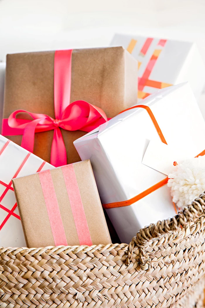 bunch of gifts placed in a basket how to wrap a gift wrapped in white and brown paper tied with red orange pink bows