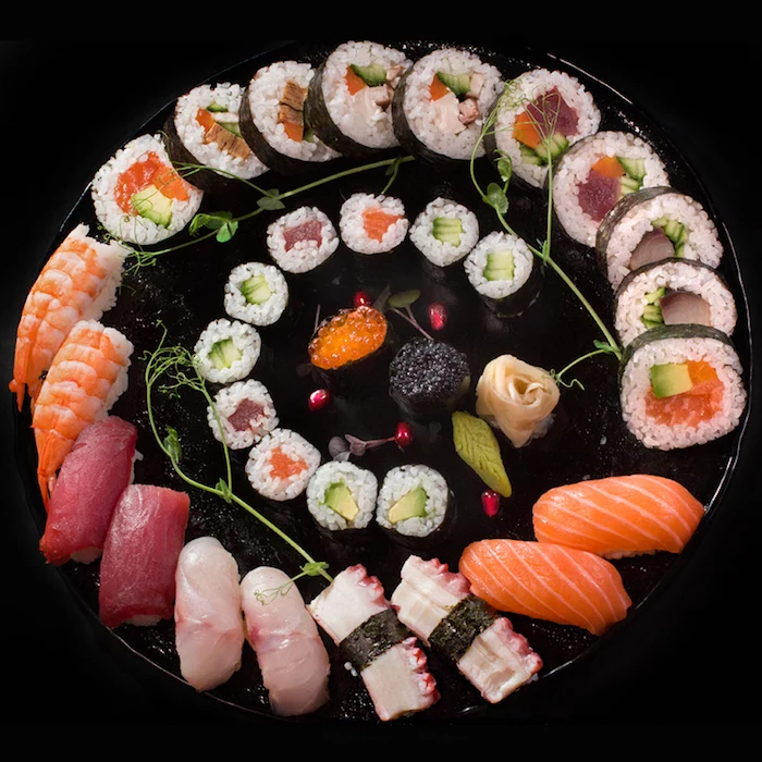 california roll recipe large round black tray with different types of sushi arranged on it in circle
