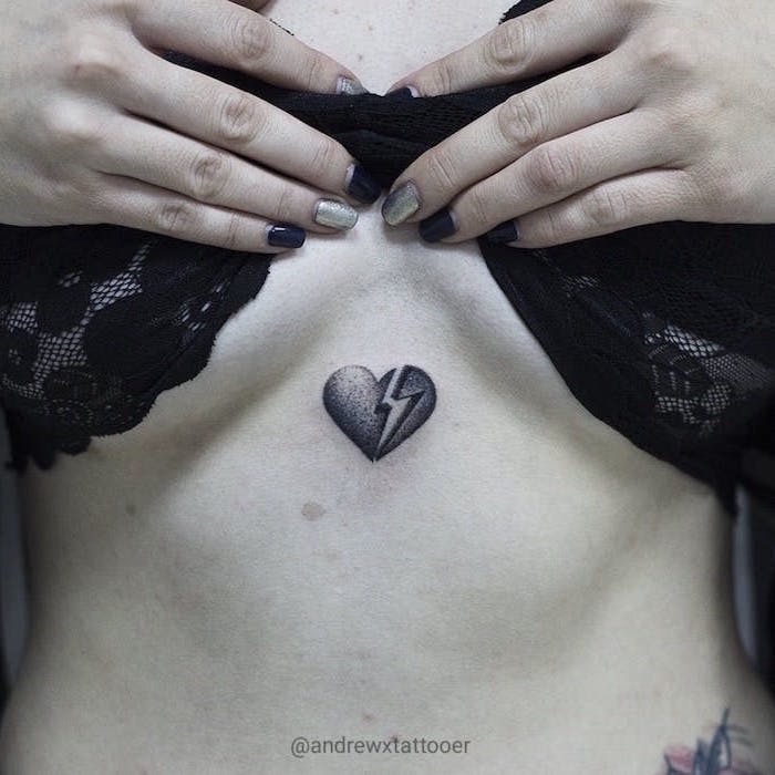 chest tattoo of small black heart broken heart tattoo on wrist flash going through it on woman with black lace top