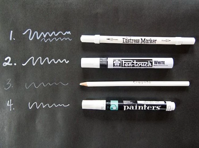 four different types of white markers placed on black wrapping paper gift wrapping ideas