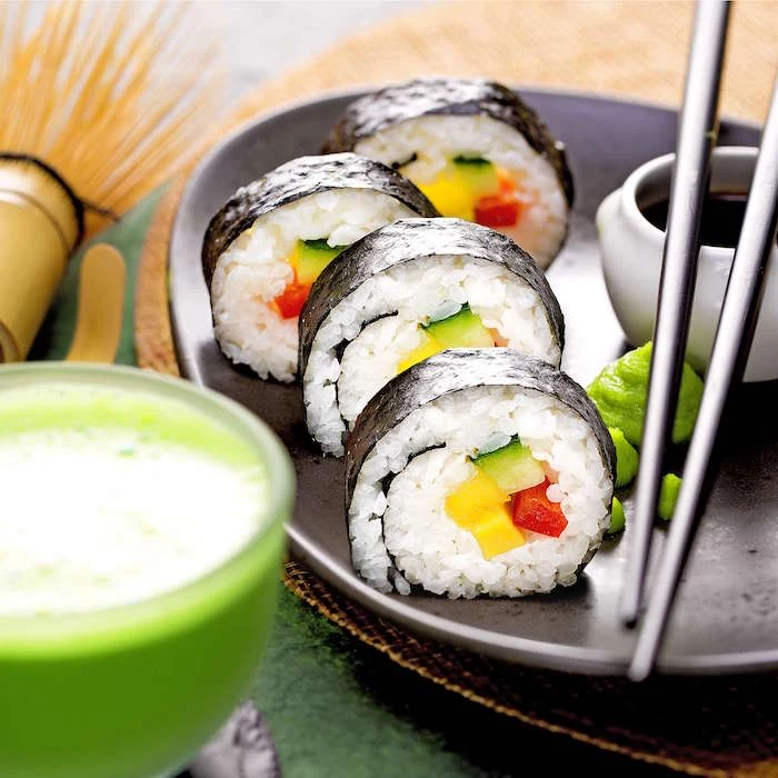 four sushi rolls with nori rice mango avocado arranged on black plate how to make sushi soy sauce black chopsticks on the side