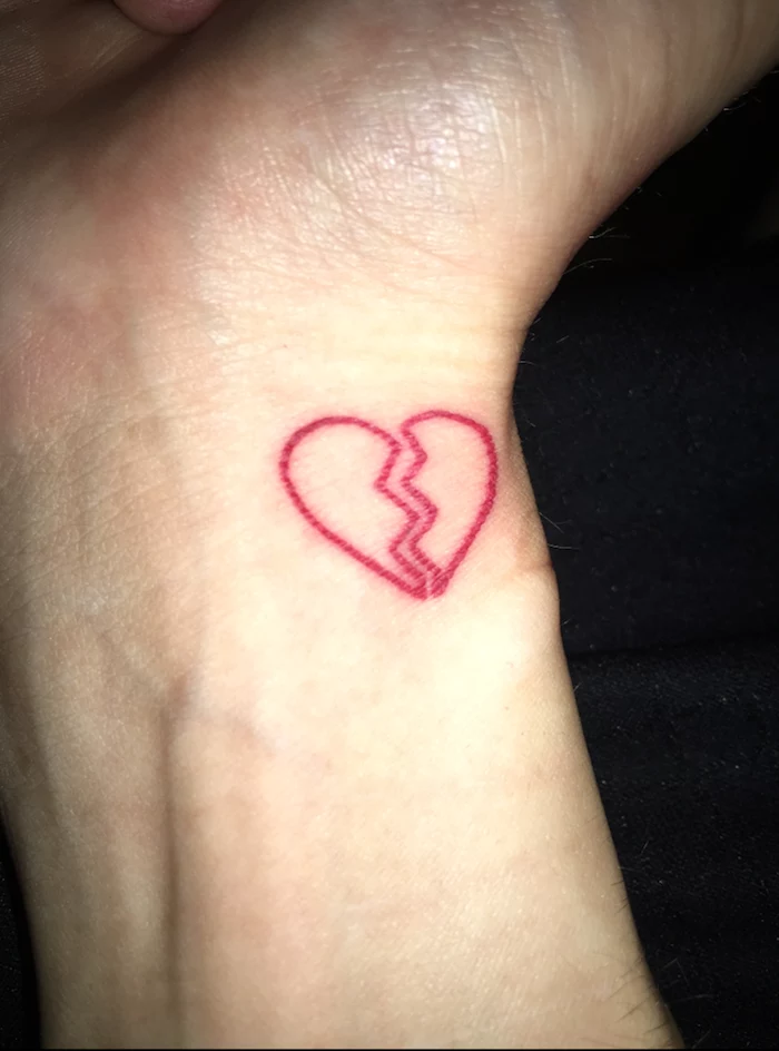 heart tattoo on wrist red outlines of small heart split in the middle black background