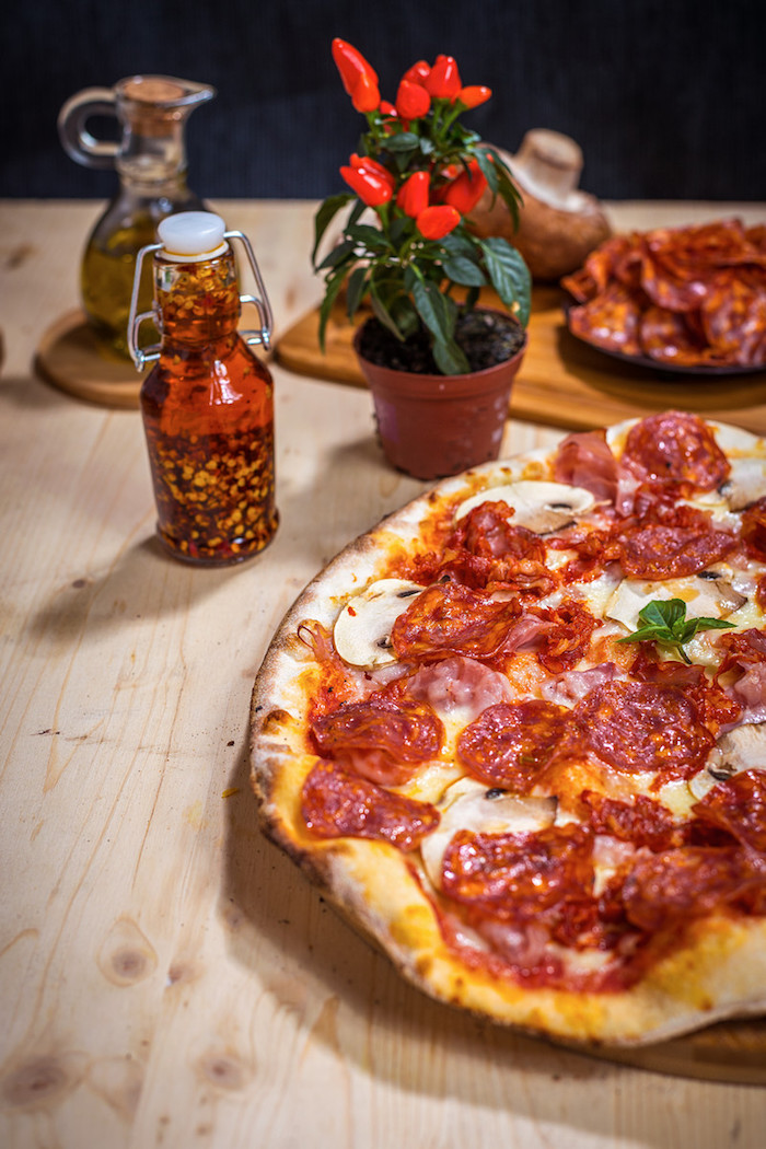 homemade pizza dough salami pizza with mushrooms placed on wooden board on wooden surface