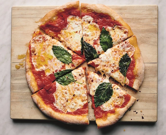 homemade pizza recipe pizza with tomato sauce mozzarella basil leaves cut into slices placed on wooden cutting board