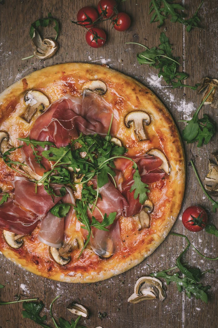 how to make pizza dough pizza with prosciutto mushrooms arugula placed on wooden surface