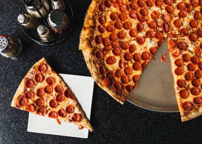 large pepperoni pizza cut into slices homemade pizza recipe placed on metal tray placed on black surface