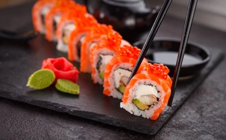 lots of sushi rolls with salmon arranged on black cutting board how to make sushi picked up with black chopsticks