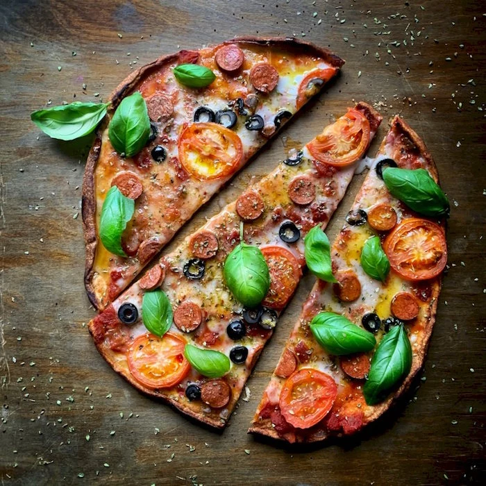 mini pizza cut into three slices pizza crust recipe with pepperoni tomatoes cheese and fresh basil leaves
