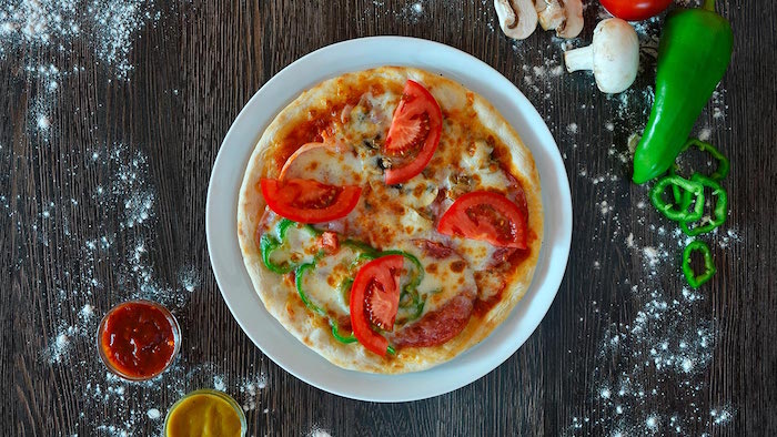 mini pizza with cheese tomatoes peppers mushrooms homemade pizza recipe placed in white plate on wooden surface