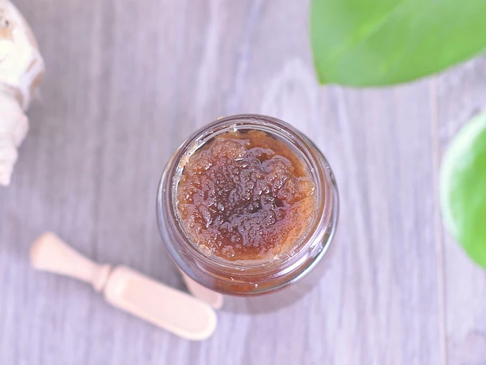 orange and brown sugar homemade lip scrub put into plastic container placed on wooden surface