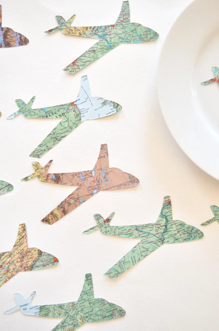 paper airplanes cut out of maps arranged on white surface next to white plate how to draw a paper airplane
