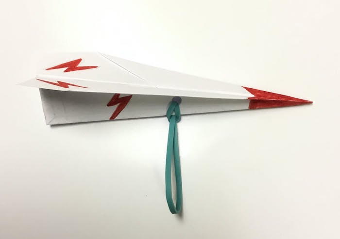 paper folded into plane drawn with red flashes and red tip simple paper airplane elastic band tied to it
