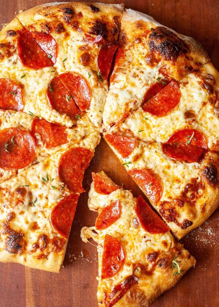 pepperoni pizza cut into slices on wooden cutting board thin crust pizza dough recipe with pepperoni lots of cheese