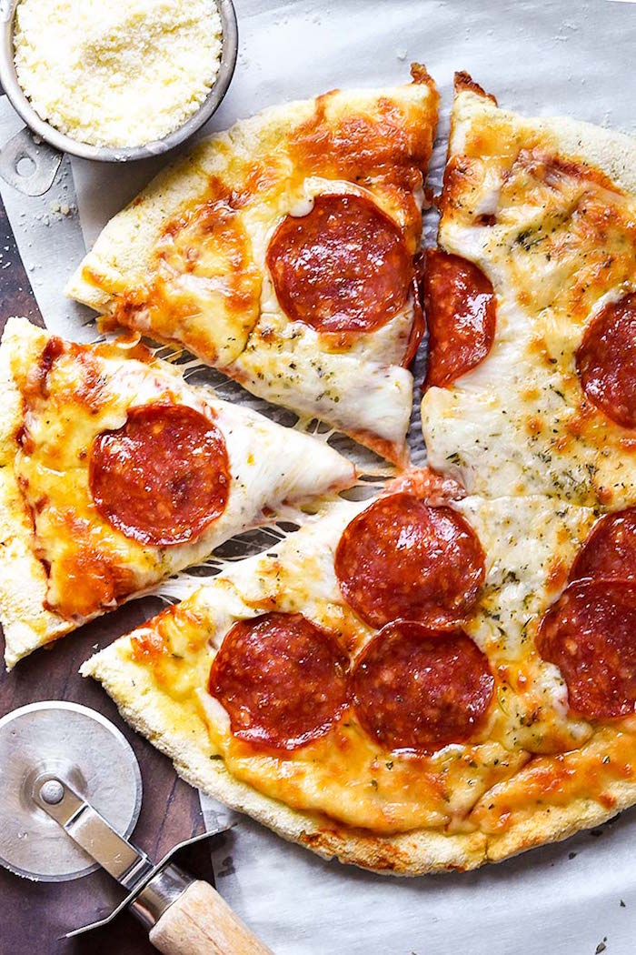 pepperoni pizza with lots of cheese pizza crust recipe placed on paper lined cutting board cut into slices