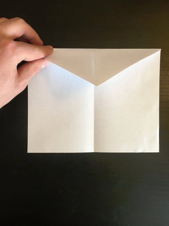 photo of hand folding white piece of paper best paper airplane design step by step diy tutorial