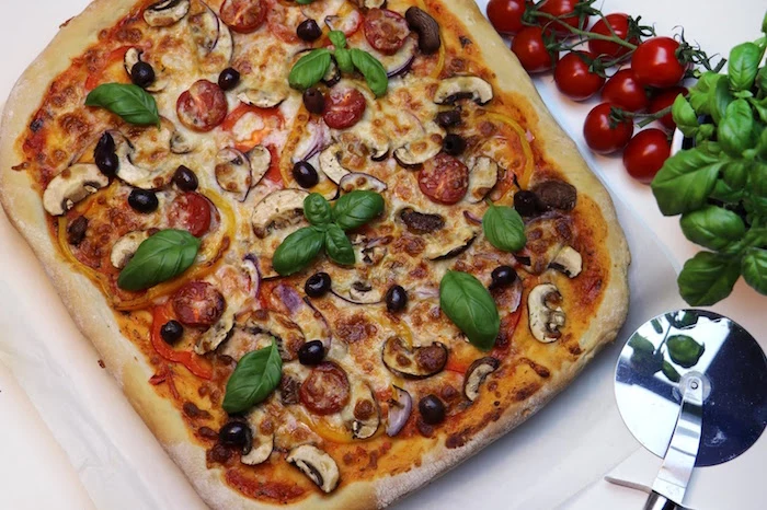 pizza crust recipe square pizza with mushrooms tomatoes olives garnished with fresh basil leaves