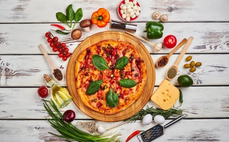 pizza garnished with basil leaves placed on wooden cutting board homemade pizza dough different toppings around it