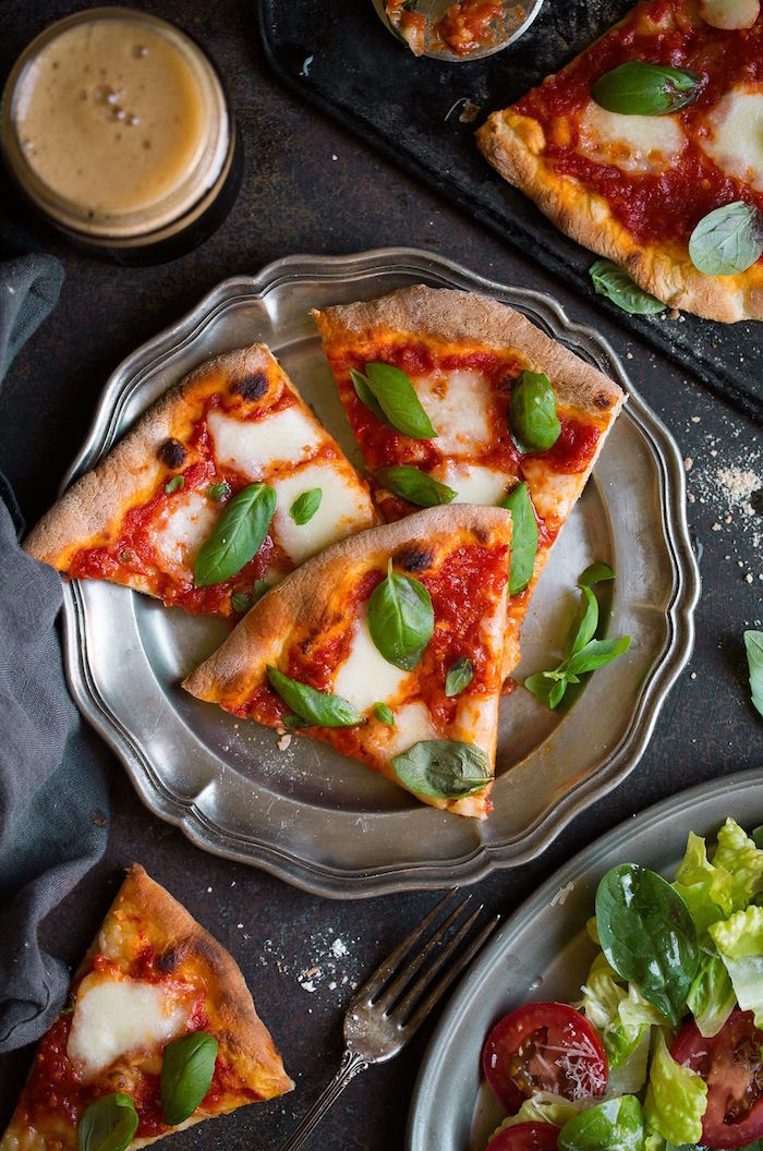 pizza margherita cut into slices placed on metal plate homemade pizza crust with mozzarella tomato sauce and fresh basil leaves