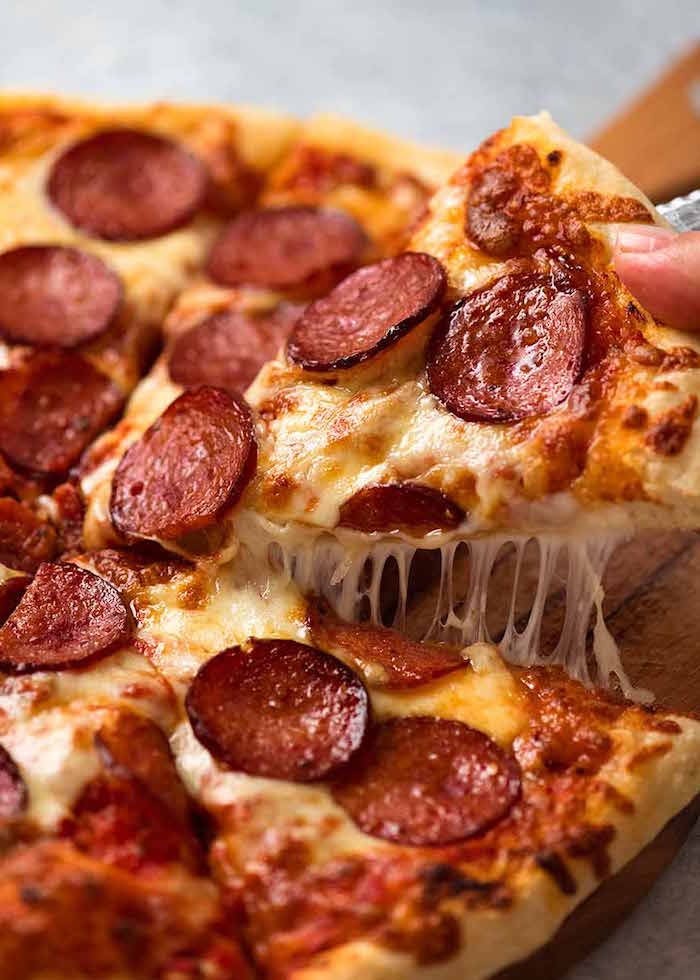 slice of pepperoni pizza with lots of cheese placed on wooden cutting board pizza crust recipe