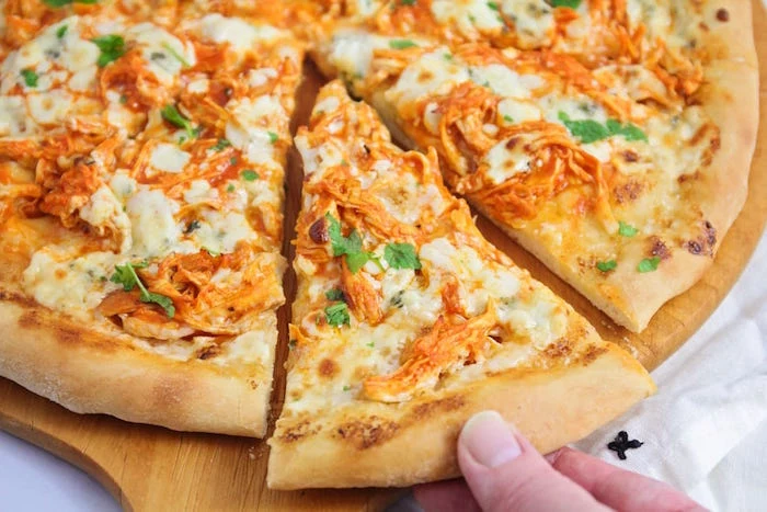 slice taken out of pizza with shredded chicken lots of cheese fresh parsley easy pizza dough recipe