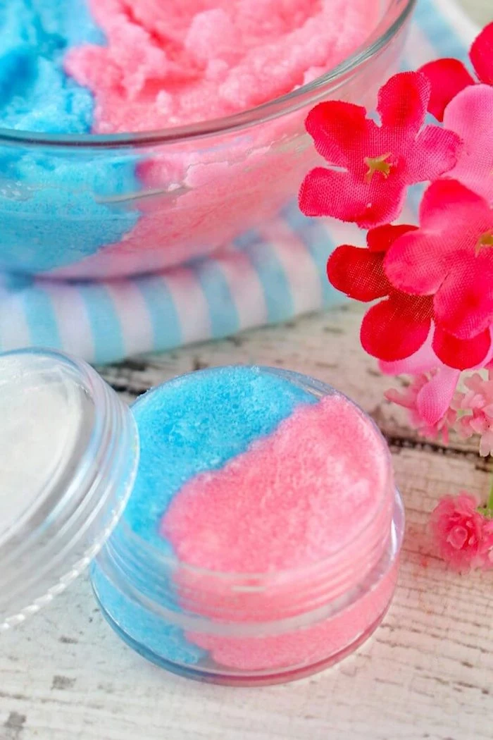 small plastic container filled with lip scrub recipe cotton candy in pink and blue placed on white wooden surface