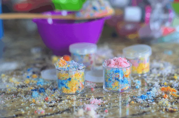 small plastic containers with unicorn diy lip scrub with coconut oil sprinkled over wooden surface