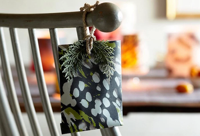 small present tied to a chair with a small branch from evergreen tree best way to wrap presents wrapped in black wrapping paper