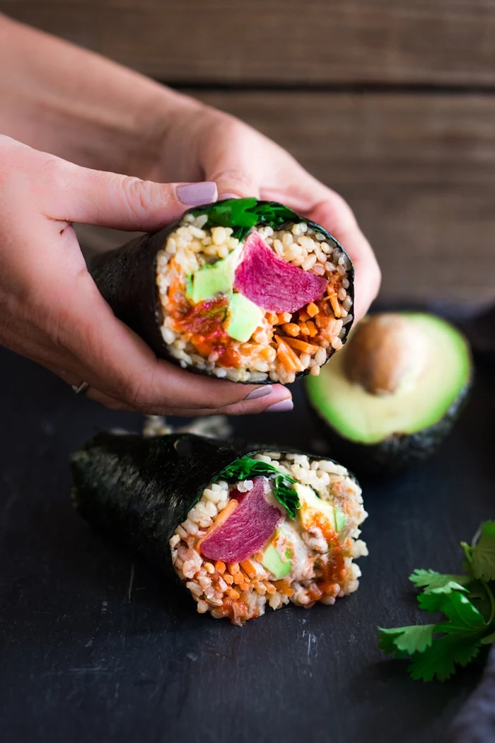 sushi burritos with rice crab meat avocado parsley california roll recipe placed on black cutting board