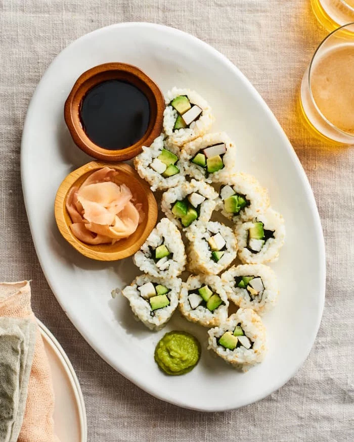 sushi rolls arranged on white plate with small wooden bowls with soy sauce wasabi dragon roll sushi