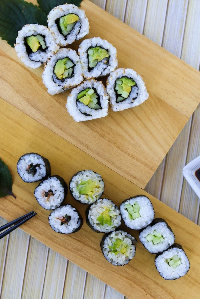 types of sushi rolls sushi with rice avocado arranged on wooden cutting boards black chopsticks on the side