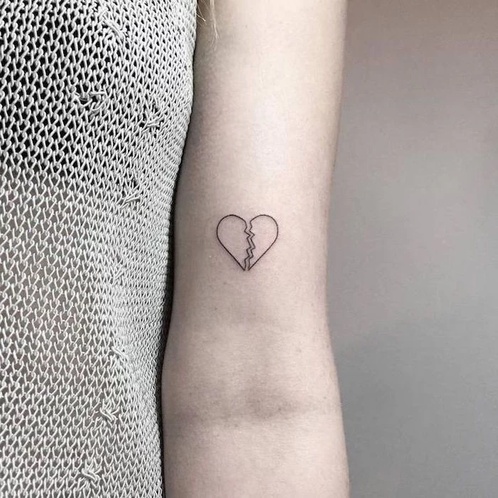 white background broken heart tattoo with black outlines not filled with ink inside the arm tattoo
