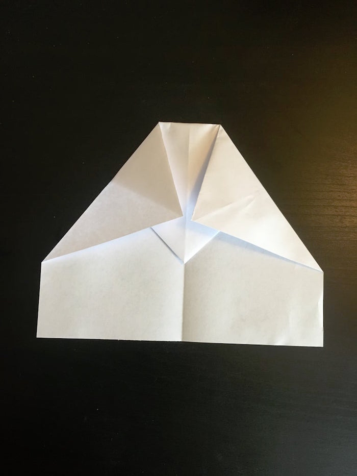 white piece of paper being folded in different ways paper airplane folding placed on black background