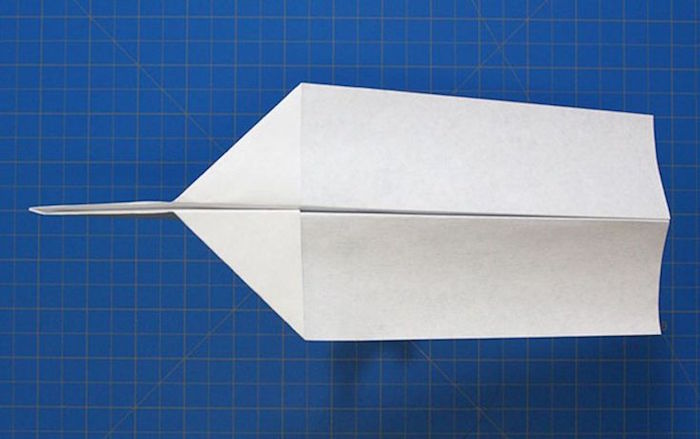 white piece of paper folded into plane step by step diy tutorial step by step paper airplane blue background