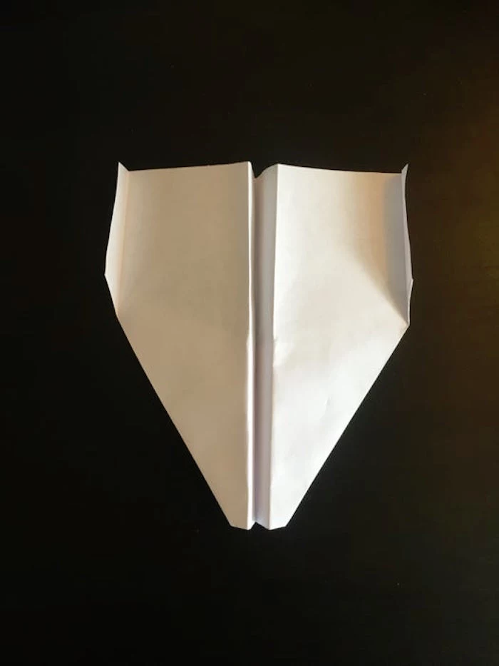 white piece of paper turned into a plane best paper airplane design photographed on black background