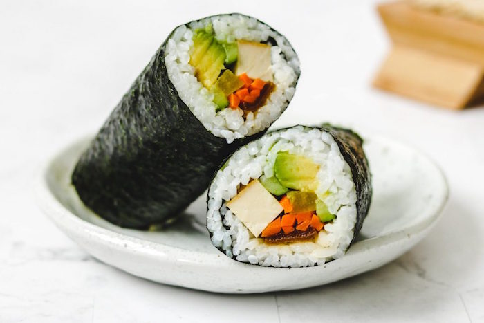white plate with vegan sushi rolls how to make sushi at home made with white rice tofu cucumber avocado carrots