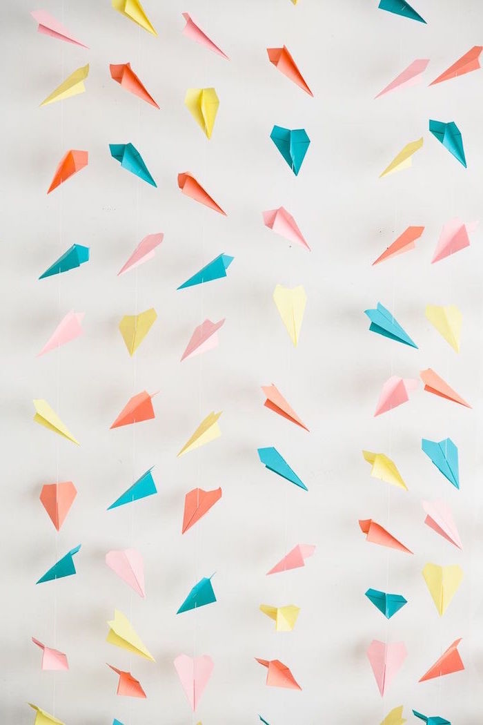 white wall in the background how to make a paper airplane blue pink yellow orange paper airplane garland