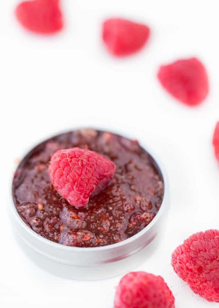 whole raspberry placed on top of homemade scrub poured inside small plastic container how to make a sugar lip scrub
