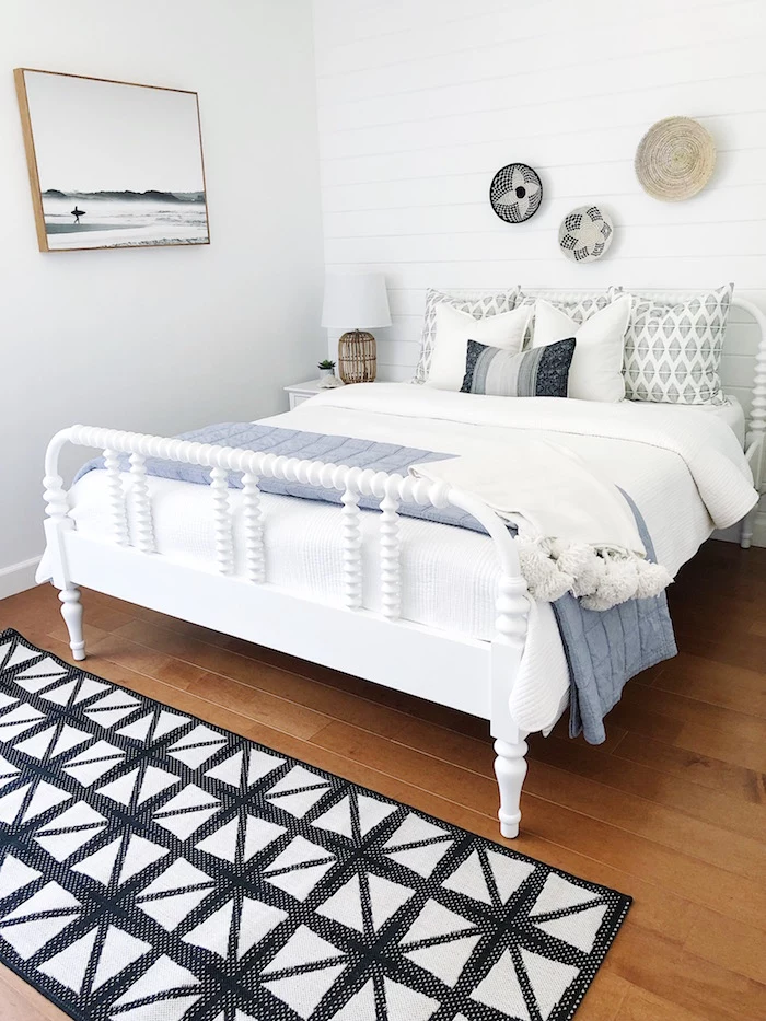 bedroom with wooden floor and white shiplap black and white carpet in front of bed with white bed frame coastal living room