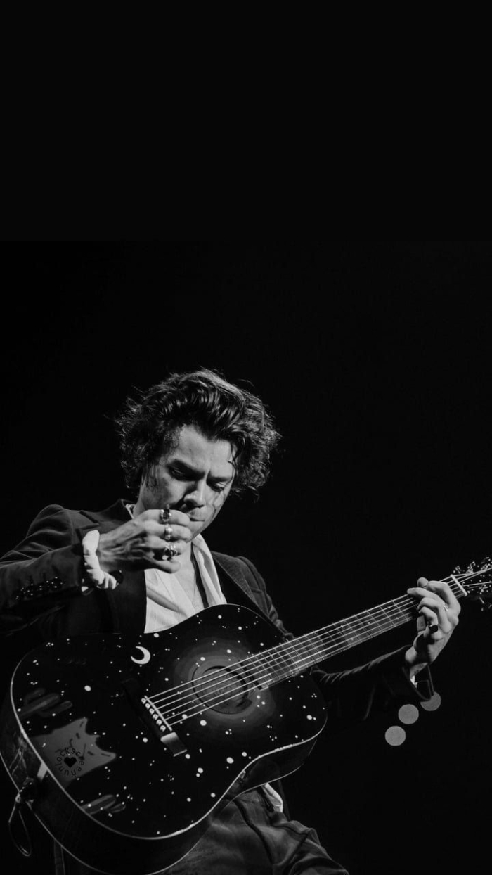 black and white photo of harry styles on stage harry styles wallpaper wearing black suit playing the guitar