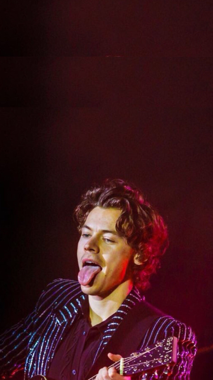 black background aesthetic harry styles on stage wearing black striped blazer black shirt sticking his tongue out