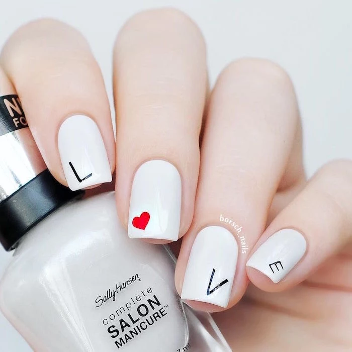 black letters spelling love on white nail polish with red heart on middle finger valentines day nails short square nails