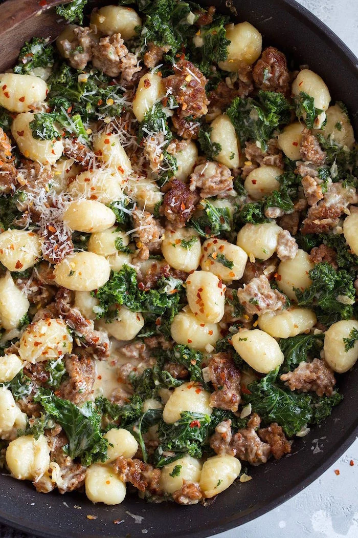 black pan easy gnocchi recipe with italian sausage kale garnished with grated parmesan cheese