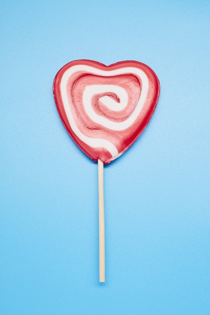 blue background cute valentines day wallpaper heart shaped lolipop in red and white in the middle
