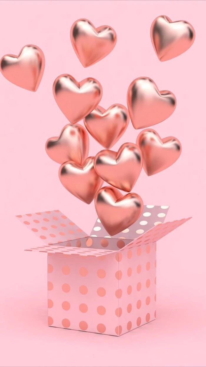 box wrapped in pink with golden dots on it filled with rose gold heart shaped balloons valentine's day origin pink background