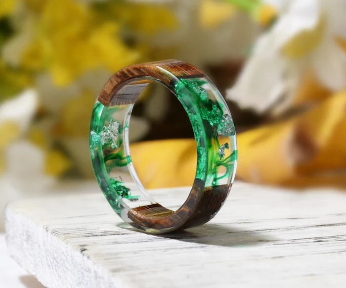 bracelet made of wood and resin resin jewelry molds clear with dried flowers inside in green and white placed on white wooden surface